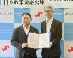 覚書締結の後、記念撮影に応じる松江商工会議所の田部会頭（左）と日本政策金融公庫松江支店の天崎支店長＝27日、松江市母衣町の松江商工会議所