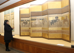 〈写真：「厩（うまや）図屏風（びょうぶ）」を紹介する佐々木学芸員＝出雲市大社町杵築西の手錢美術館〉