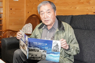 〈写真：写真集「日本海・竹島のアシカ猟」を手にする佐藤さん〉