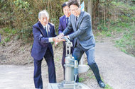 〈写真：設置された防災井戸から水をくむ、左から服部自治会長、飯塚市長、石倉部会長＝16日、出雲市小伊津町の自治会管理地〉