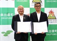 〈写真：協定書を手に記念撮影する「ツルハグループドラッグ＆ファーマシー西日本」の光永研一部長（右）と糸原保町長＝15日、奥出雲町役場仁多庁舎〉
