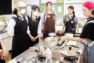〈写真：ワークショップで調理実習を行う大学生と高校生＝24日、大田市仁摩町の県立邇摩高校〉