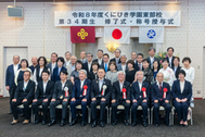 〈写真：称号授与式の後、丸山知事を囲んで記念写真に納まる新マイスター＝28日、松江市殿町のサンラポーむらくも〉
