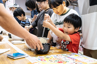 〈写真：農業の魅力に親しんでもらおうと、コメをすくい、３００グラムの重さ当てに挑戦するコーナーなどが設けられた＝20日、松江市学園南のくにびきメッセ〉
